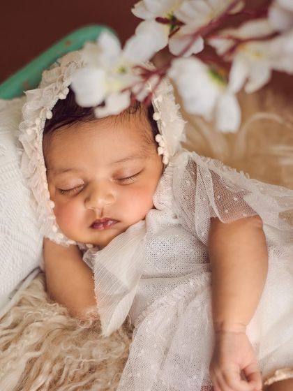 An angelic portrait. This baby is dressed in a beautiful white lace bonnet and dress, creating a soft, ethereal, and timeless look.