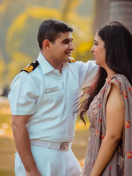 This is another beautiful shot from the couple's pre-wedding session, showcasing the groom's summer uniform. The warm, golden hour light and natural park setting create a soft and romantic atmosphere, perfect for capturing these quiet, shared glances.