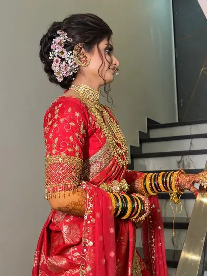 The side profile of this bride in a red Nauvari highlights her intricate floral hair bun.