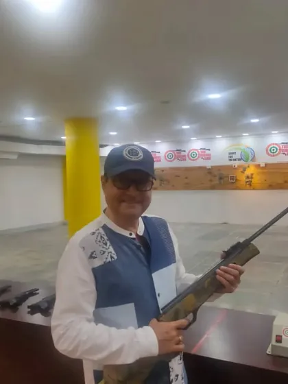 A smiling Sachin Pilgaonkar holding an air rifle at our indoor range. We are a popular spot for a unique recreational activity in Mumbai.