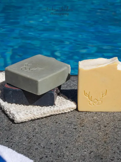 A shot of stacked handmade soaps, showcasing their different colors and textures against the backdrop of the water. This is a great way to display a product collection.