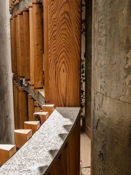 A close-up of the wooden louvres and concrete structure of the Outré House, showing the craftsmanship and material texture that define the project.