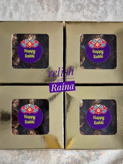 Small, elegant golden boxes of my Protein Laddoos, customized with "Happy Rakhi" stickers. A healthy and modern gift for the festival.