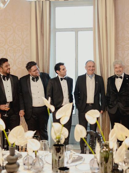 A group of men in tuxedos enjoying the black and white themed pre-wedding dinner.