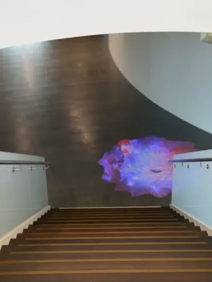 The 'Amorphous Color Rain' projection seen from the top of the stairs at Virchow 16. The artwork acts as a destination and a point of interest within the building's main circulation volume.
