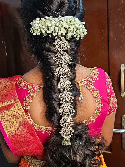 A South Indian bridal look is incomplete without the perfect hairstyle. Here is a classic bridal braid, intricately decorated with beautiful jada billai and fresh jasmine flowers for that authentic and fragrant touch.