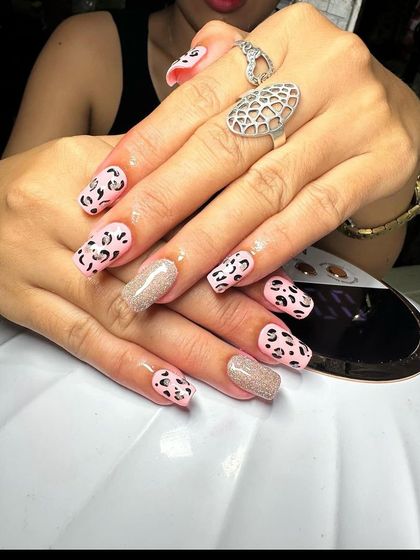 A fun take on leopard print with a pink base and a glitter accent nail. This demonstrates how to adapt classic patterns to different color schemes.