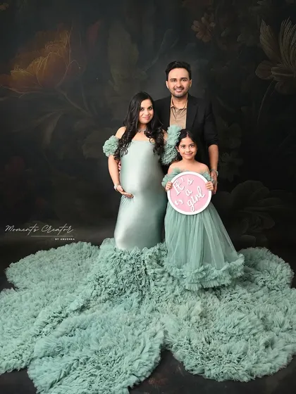 "It's a girl!" This beautiful family portrait serves as a joyful gender reveal, with the older sister holding the sign and everyone dressed in coordinating pastel green.