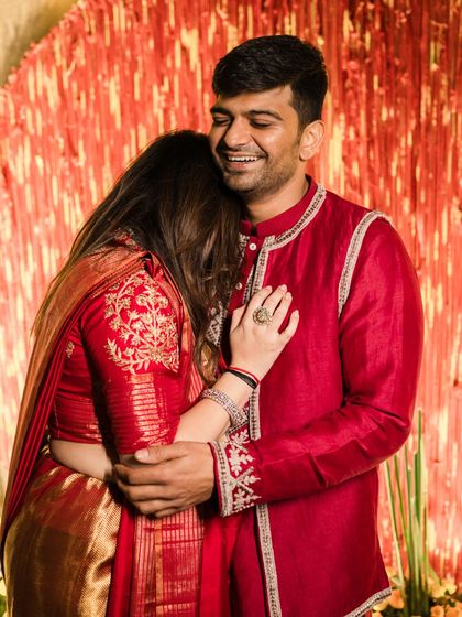 A warm embrace between the couple, their coordinated red outfits creating a powerful and romantic statement.