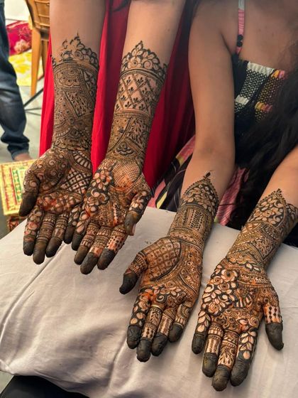 A group shot showcasing two sets of full-coverage henna, perfect for a bride and her sister or friend.