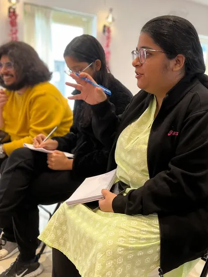A writer passionately sharing her thoughts during a group discussion. Our workshops are interactive, encouraging every participant to contribute and learn from one another.