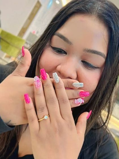 A happy client showing off her new pink glitter and 3D floral nail extensions.