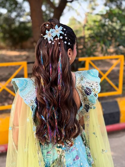 A close up of the detailed accessory work in the carnival hairstyle. The combination of flowers, pearls, and threads creates a rich, textured look.