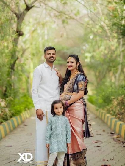 A happy family portrait with their young child, taken on a beautiful tree-lined avenue.