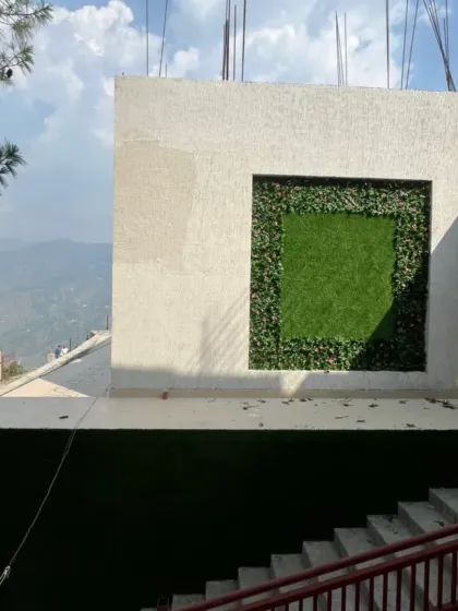 A wider view of the framed installation in the mountains of Himachal Pradesh. It serves as a striking architectural feature on the building's exterior.