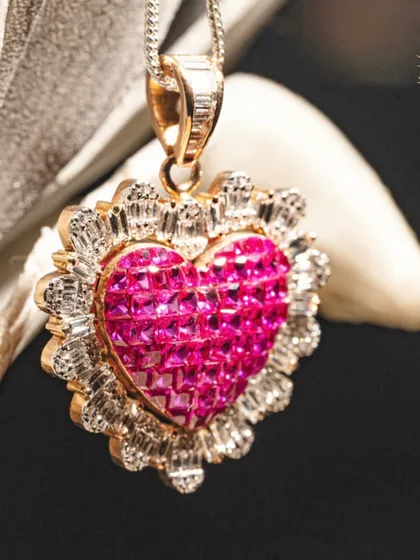 A heart full of fire. This pendant is crafted with invisibly set princess-cut rubies to create a seamless, sparkling heart, framed by a halo of baguette-cut diamonds. It is a technical feat and a timeless symbol of love.