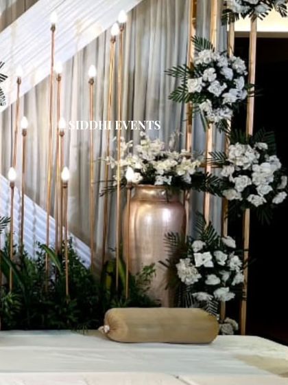 This angle highlights the beautiful contrast between the warm metallic vase, the pure white floral arrangements, and the soft glow of the lighting.
