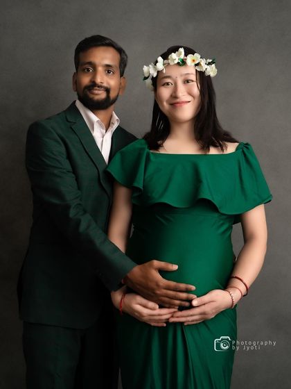 A formal studio portrait of an expecting couple, perfect for a classic and elegant maternity announcement.