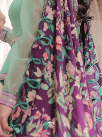 A close-up of the intricate cut-work detailing on the floral dupatta, a testament to the fine craftsmanship of the ensemble.