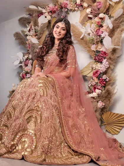 A full-length view of the stunning dusty pink and gold lehenga, set against a beautiful floral backdrop. This is the epitome of elegance and grace for any modern celebration.
