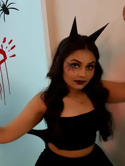 A full view of the Halloween costume makeup, featuring a spiderweb eye design, bloody handprints, and spider props for a complete spooky effect.