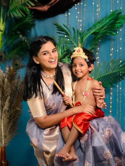 A joyful portrait of mother and son from their Janmashtami themed baby shoot. The vibrant backdrop and traditional costumes make these photos stand out.