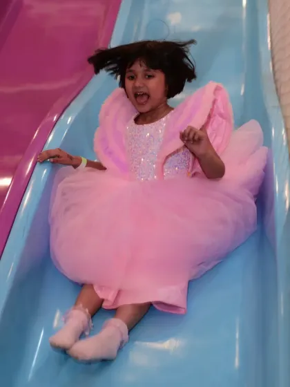Whee! A birthday girl in her beautiful pink dress enjoying a trip down one of our multi-colored slides. Safety and fun go hand-in-hand here.