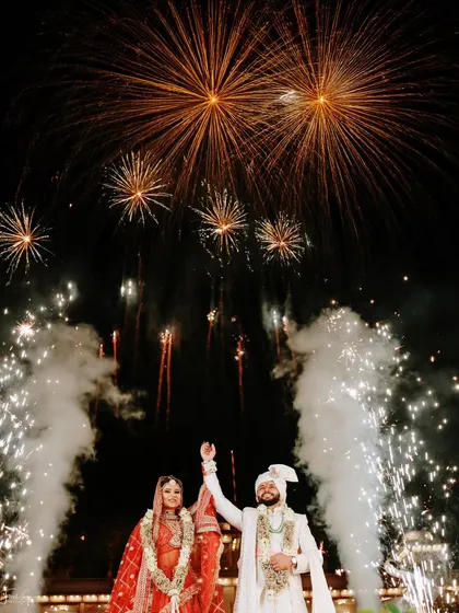 A triumphant moment for the couple, framed by a spectacular fireworks display. Capturing these grand, perfectly timed shots is a hallmark of our premium wedding photography experience.