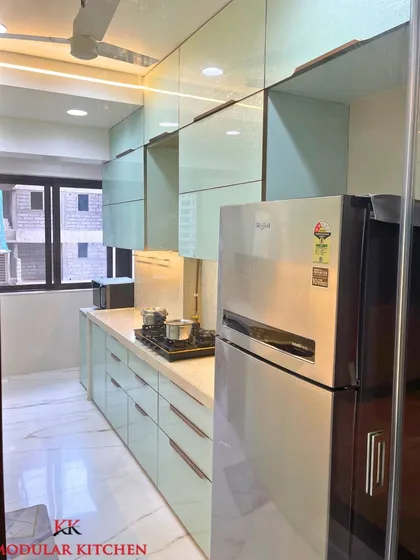 A view of the refrigerator and upper cabinets in our Ghatkopar project. The textured glass finish adds a unique touch to the overall design.