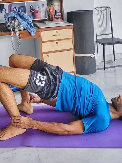 A student holding a supported Bridge Pose, using their hands to deepen the backbend. This is a great example of how we use simple techniques to enhance foundational postures.