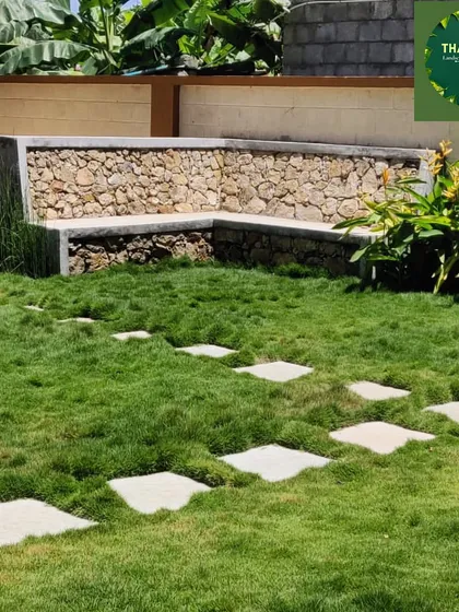 This custom-built L-shaped bench is made from locally sourced stones, providing a permanent and beautiful seating area that blends perfectly with the natural lawn and stepping stones.
