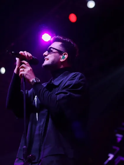A singer caught in a moment of reflection between verses, bathed in soft purple light. These are the subtle emotional shifts I aim to capture during a set.