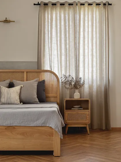 A wider view of the Japandi-style master bedroom, showing the beautiful herringbone wood floors, the light-filtering jute curtains, and the overall serene and collected feel of the space.