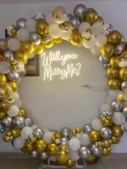 A close-up view of the neon sign and the mix of confetti, chrome, and standard balloons used to create a full and luxurious look for your marriage proposal.