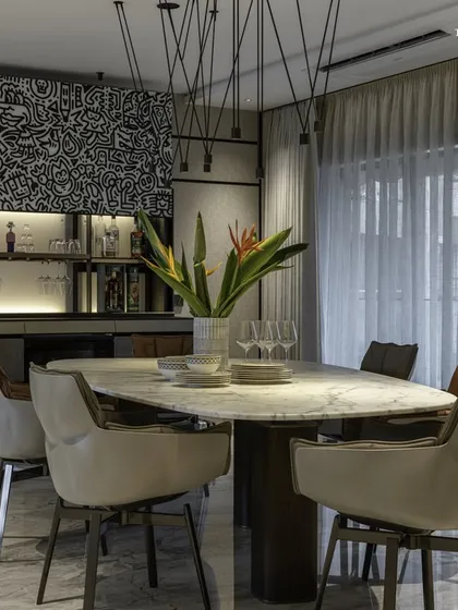 The dining area in this bachelor pad extends into an expansive lounge space. A nearby Valcucine bar counter, adorned with doodle art, steals the spotlight, echoing the home's understated elegance and making it perfect for entertaining.