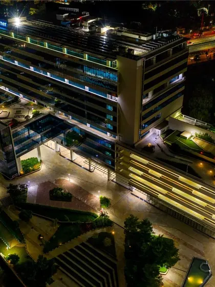 An elevated perspective of the same office complex, capturing the rooftop details, courtyard, and the multi-level parking structure, all beautifully lit.