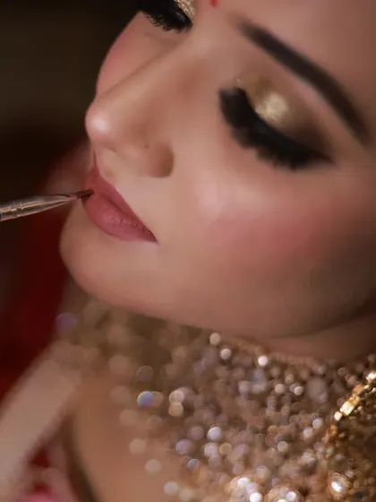 The final touch on a bridal look. This close-up shows the precise application of lipstick, a key step in creating a defined and long-lasting pout for the wedding day.