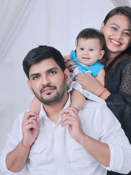 A bright and happy family portrait with a clean, white curtained background. The baby enjoys a fun shoulder ride, creating a joyful and dynamic photo.