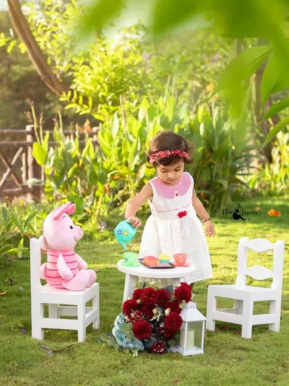 A wider view of the enchanting outdoor tea party setup. The natural light and beautiful greenery create a perfect storybook scene for her second birthday.