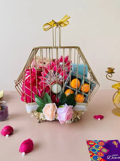 My metal hexagon box, designed to look like a birdcage, is a unique packaging option. I've filled this one with laddoo-shaped sweets, a diya, and flowers.