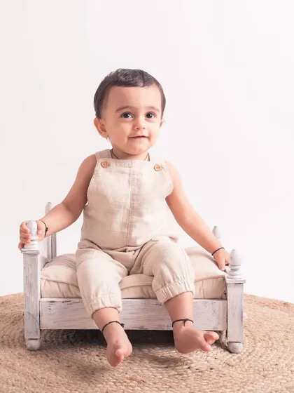 A simple and elegant portrait of a one-year-old on a miniature bed, set against a clean, neutral background.