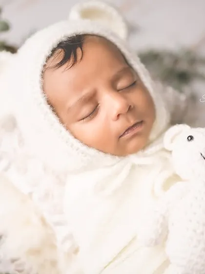 This little bear is hibernating! A cozy bonnet and a tiny teddy friend make this newborn portrait extra special and heartwarming.