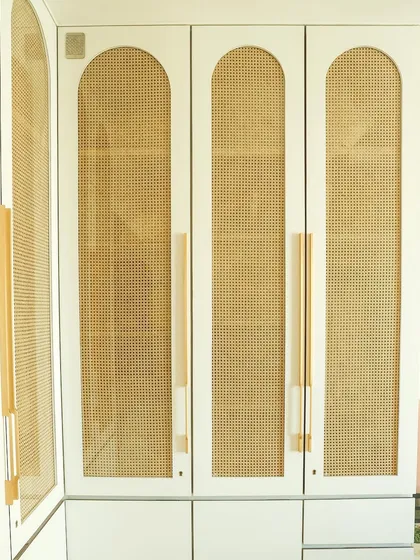 A detailed shot of the arched wardrobe doors, showcasing the beautiful texture of the rattan cane against the clean white frame.