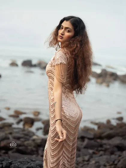 A beautiful portrait of the model looking back over her shoulder, with her sequined dress catching the last rays of sunlight. The image has a warm, golden-hour glow.