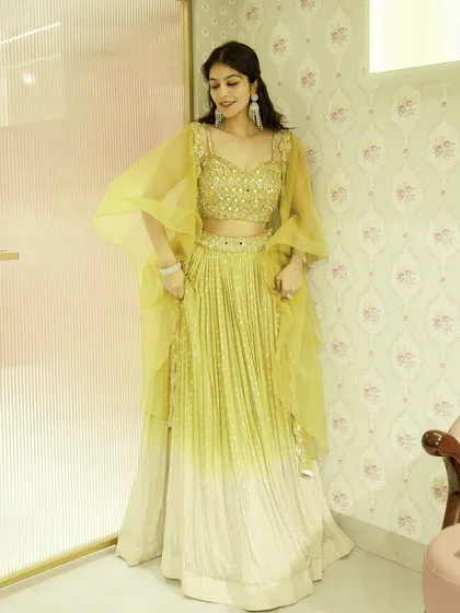This lime green and beige ombre lehenga is a fantastic choice for a day wedding or a Haldi ceremony. The cape-style sleeves add a unique, modern flair to the traditional outfit.