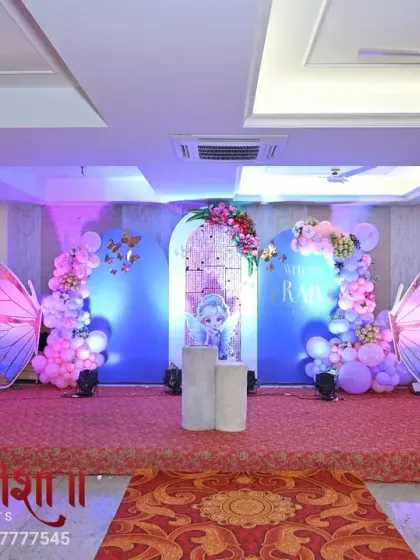Another perspective of the butterfly princess birthday setup. The lighting highlights the iridescent quality of the large wing props and the soft colors of the balloon decor, perfect for an indoor banquet hall.