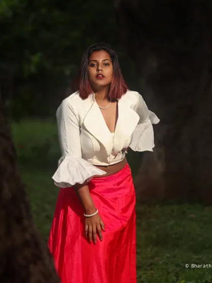A portrait focusing on the upper body, showcasing the unique design of the ruffled white top and the model's expression.