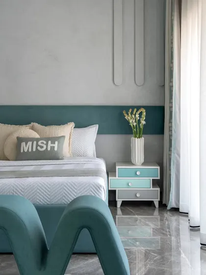 The bed in this kids' room is a statement piece, with its unique headboard and personalized cushion. The design is modern, comfortable, and full of character.
