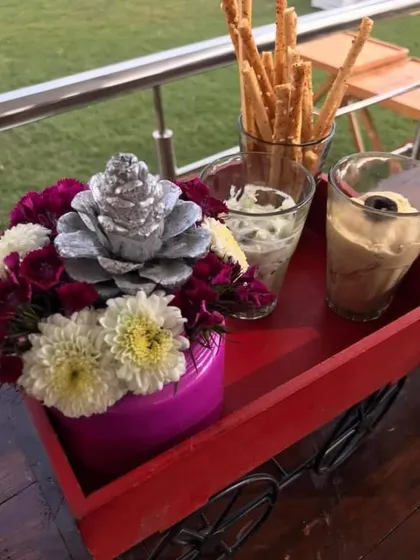 A small detail from a spring party setup. This little red cart holds breadsticks and dips, with a pretty floral arrangement adding a pop of colour.