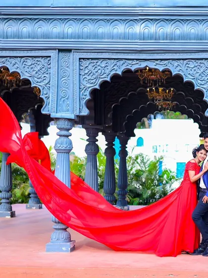 A grand, wide-angle shot featuring the bride's flowing red gown in a beautiful stone gazebo. This showcases both the outfit and the stunning location.